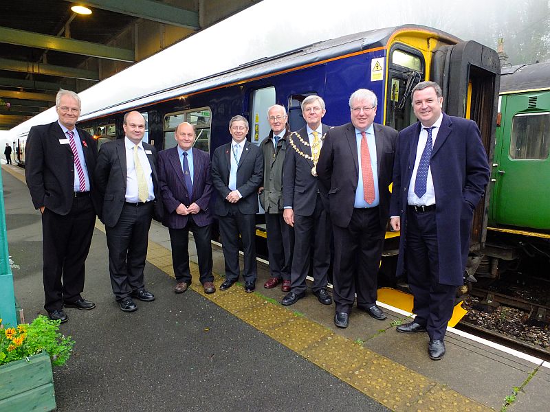 The party at Okehampton station. l to r: Bruce Thompson (Head of Transportation service DCC); Mark Hopwood (Managing Director of FGW);  Cllr Dr Michael Ireland (OTC, Chair of Destination Okehampton); Cllr Kevin Ball (DCC - Okehampton Rural, WDBC, OTC); Cllr John Clatworthy (DCC - Dawlish); Cllr Paul Vachon (Mayor of Okehampton); Patrick McLoughlin (MP, Secretary of State for Transport); Mel Stride (MP for Central Devon).  